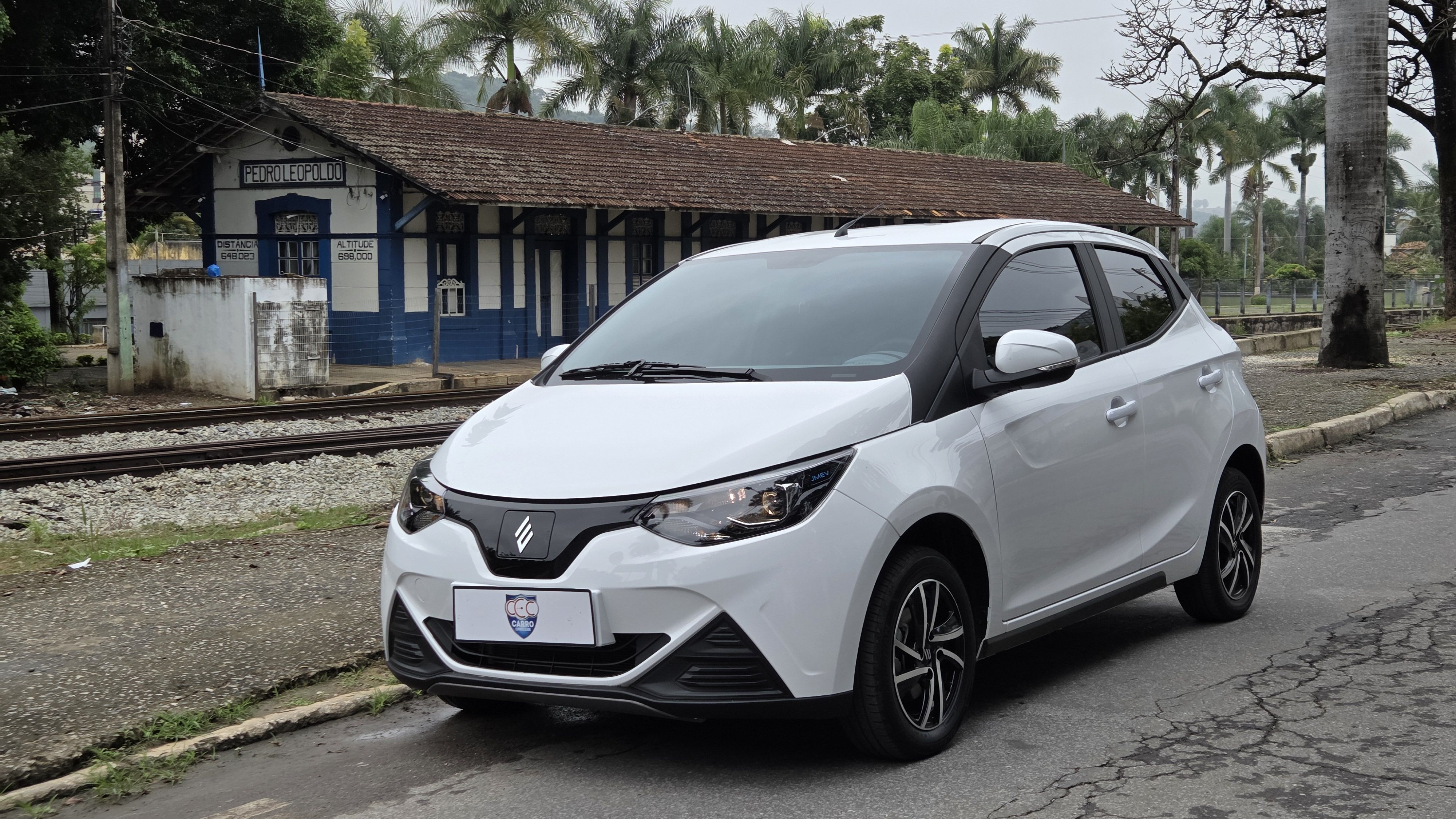 JMEV EV2 blanco estacionado frente a estación de tren